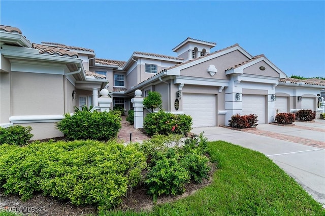 view of front of house featuring driveway, a tiled roof, an attached garage, and stucco siding