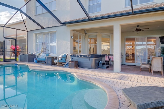 outdoor pool with a hot tub, glass enclosure, ceiling fan, and a patio area