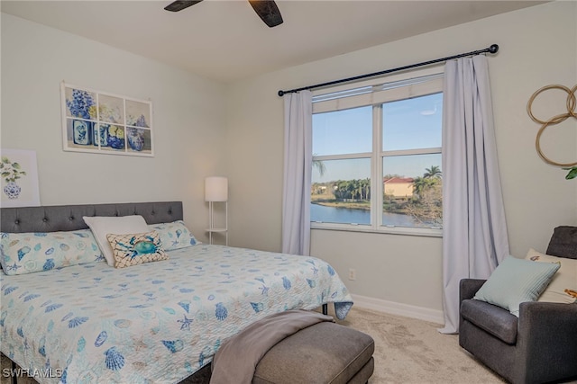 bedroom featuring a ceiling fan, a water view, light carpet, and baseboards