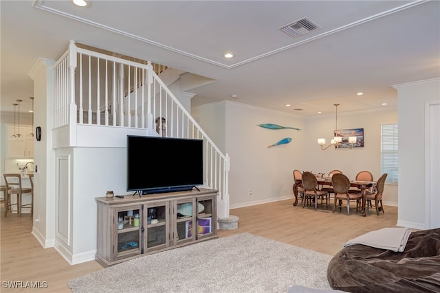 living room with ornamental molding, light wood-type flooring, visible vents, and stairs