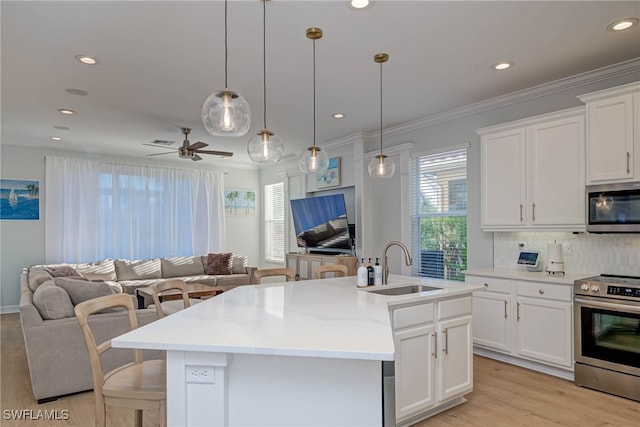 kitchen with white cabinets, an island with sink, appliances with stainless steel finishes, open floor plan, and light countertops