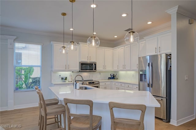 kitchen featuring white cabinets, appliances with stainless steel finishes, light countertops, and pendant lighting