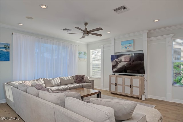 living room featuring a healthy amount of sunlight, visible vents, and crown molding