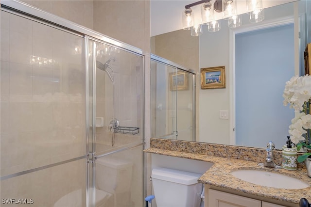 bathroom featuring a shower stall, toilet, and vanity