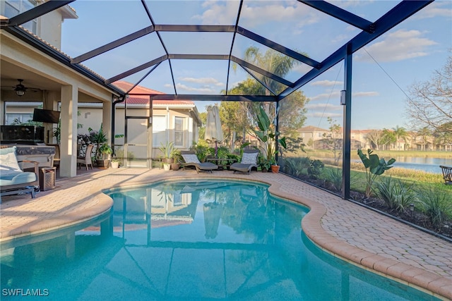 pool featuring glass enclosure, a patio area, and a water view