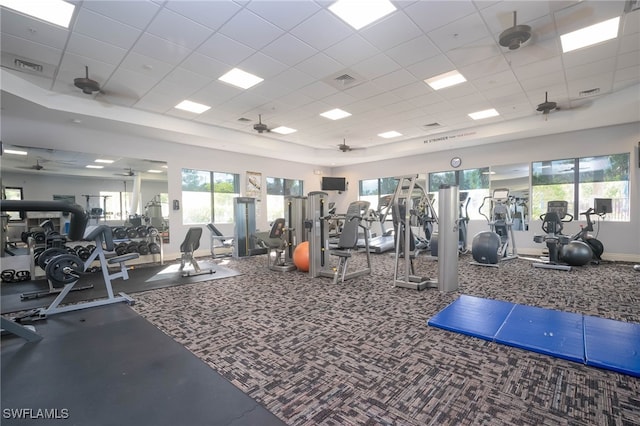 exercise room featuring ceiling fan, a drop ceiling, visible vents, and baseboards