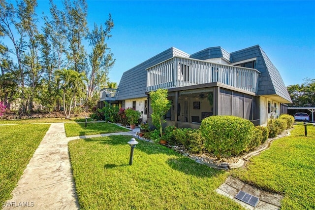 rear view of property featuring a balcony, a yard, and a sunroom