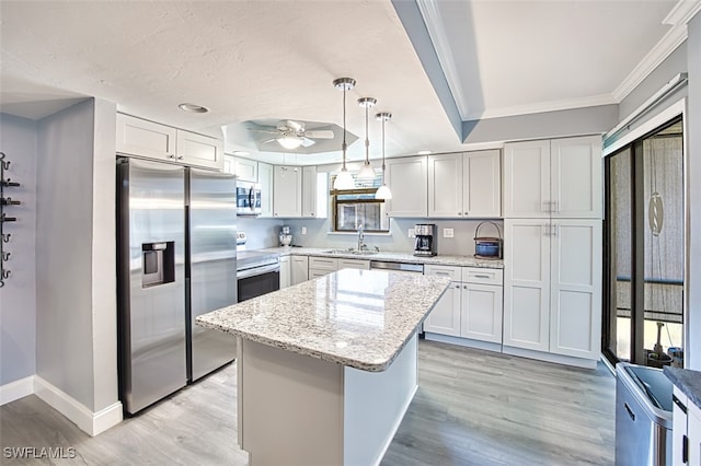 kitchen featuring sink, white cabinetry, a center island, hanging light fixtures, and appliances with stainless steel finishes