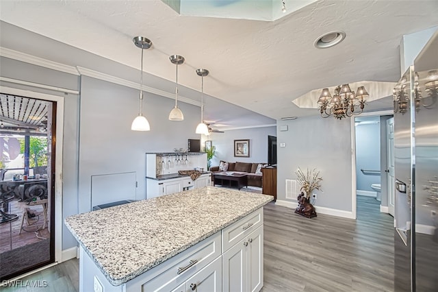 kitchen featuring white cabinetry, a center island, dark hardwood / wood-style flooring, pendant lighting, and light stone countertops