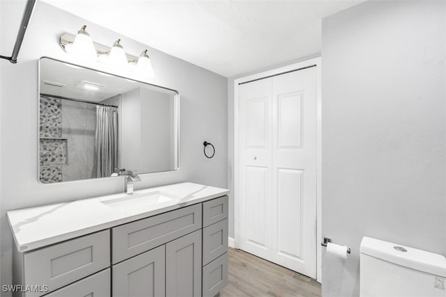 bathroom with a shower with curtain, vanity, hardwood / wood-style floors, and toilet