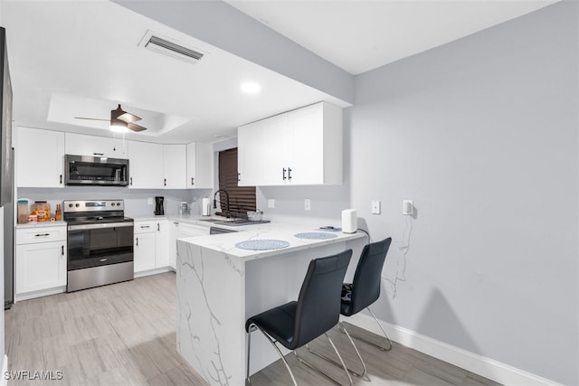 kitchen featuring white cabinetry, sink, a breakfast bar area, kitchen peninsula, and stainless steel appliances