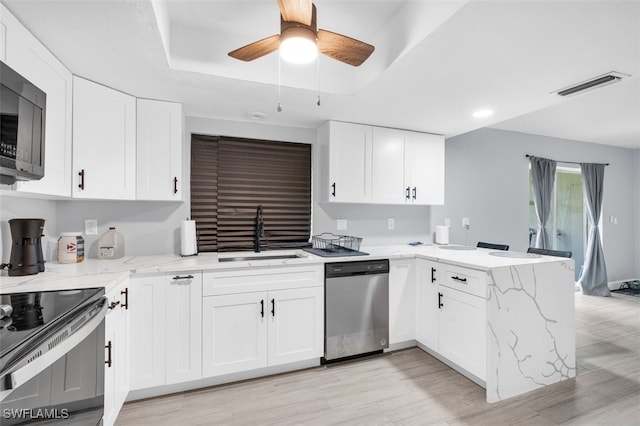 kitchen featuring sink, appliances with stainless steel finishes, kitchen peninsula, a raised ceiling, and white cabinets