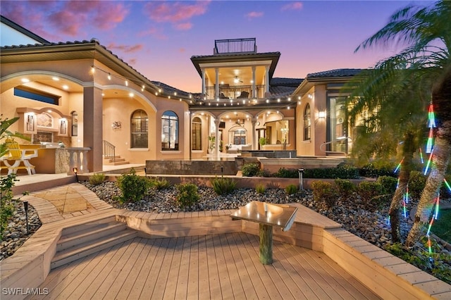 back house at dusk featuring a balcony