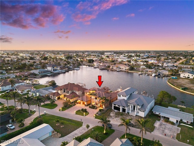 aerial view at dusk featuring a water view