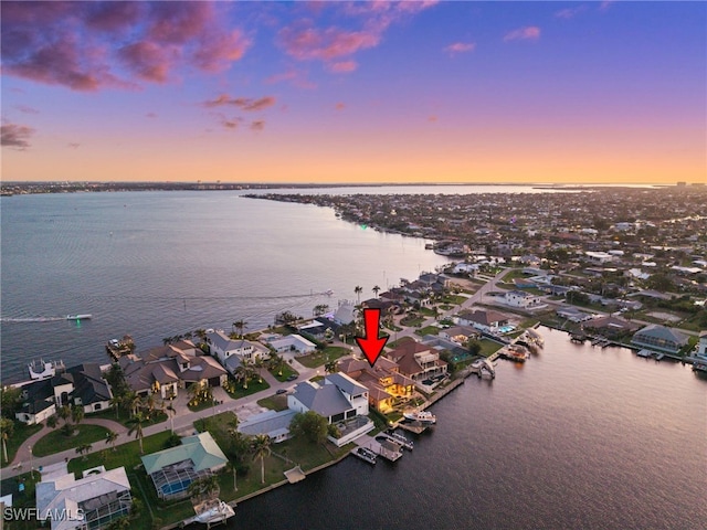 aerial view at dusk featuring a water view