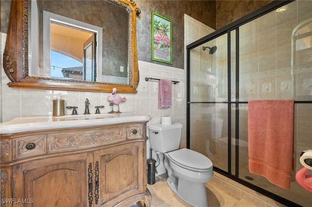 bathroom with toilet, a shower with shower door, tile walls, tile patterned floors, and vanity