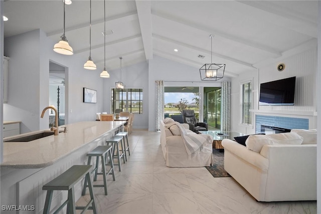 living area featuring high vaulted ceiling, a glass covered fireplace, marble finish floor, and beamed ceiling