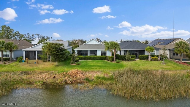 back of house with a water view and a yard