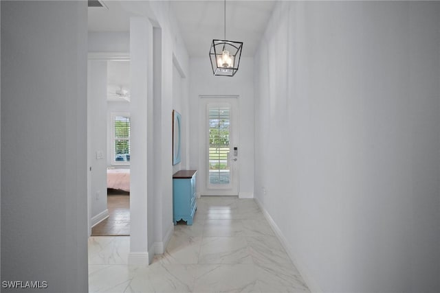 entryway featuring a notable chandelier, marble finish floor, and baseboards