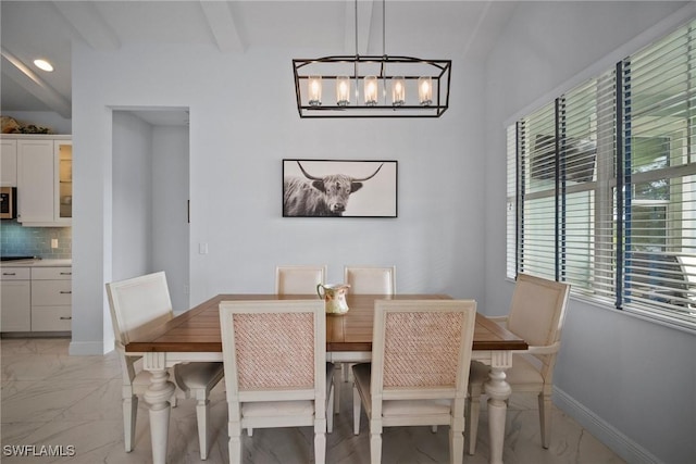 dining room featuring a chandelier, marble finish floor, beamed ceiling, and baseboards