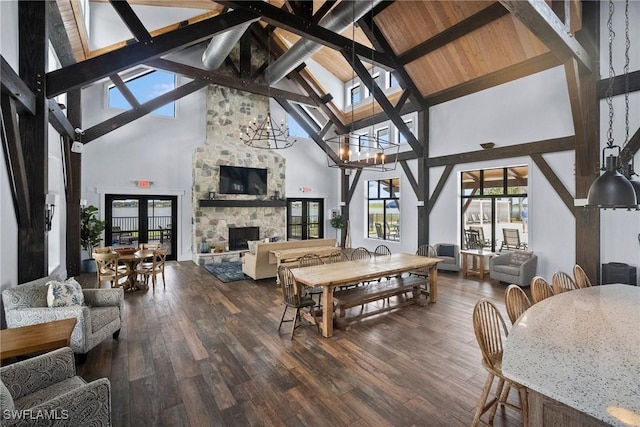 sunroom / solarium featuring french doors, a fireplace, lofted ceiling with beams, and an inviting chandelier