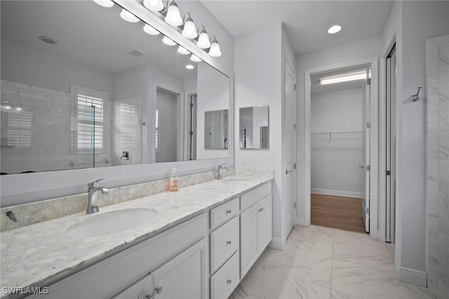 full bath featuring a sink, double vanity, walk in shower, and a walk in closet