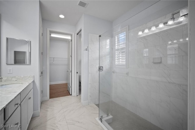 bathroom featuring visible vents, a spacious closet, a shower stall, vanity, and baseboards