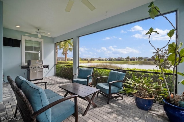 sunroom / solarium with a water view and ceiling fan