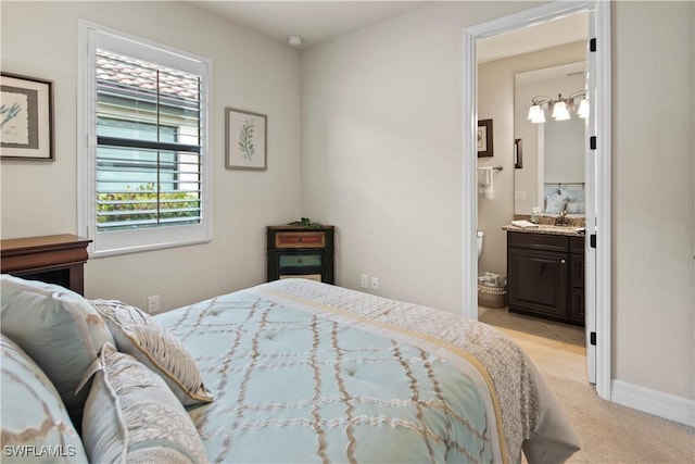 bedroom featuring connected bathroom, sink, and light colored carpet