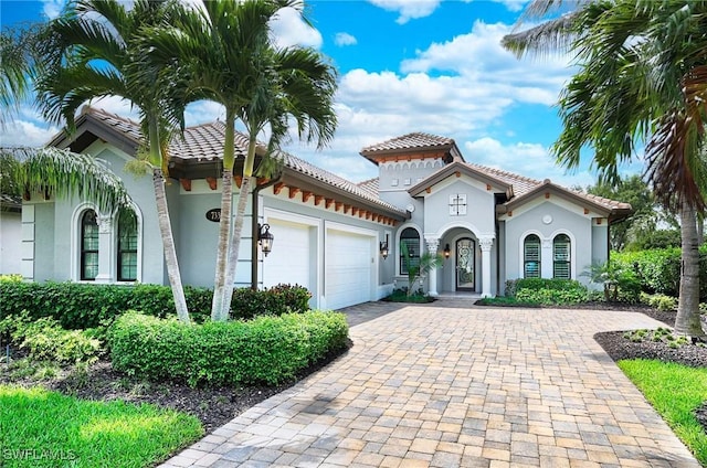 mediterranean / spanish-style home featuring stucco siding, a garage, driveway, and a tiled roof