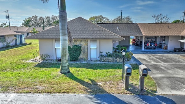 ranch-style house with driveway, a shingled roof, a front lawn, a carport, and stucco siding