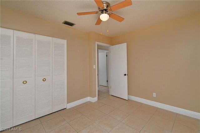 unfurnished bedroom with light tile patterned floors, a textured ceiling, visible vents, baseboards, and a closet