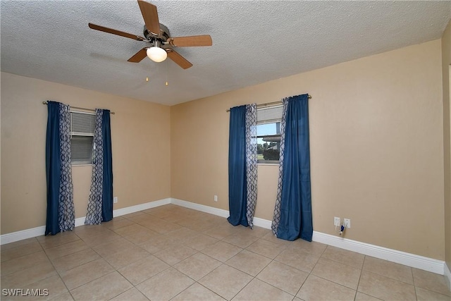 spare room with light tile patterned floors, baseboards, and a textured ceiling