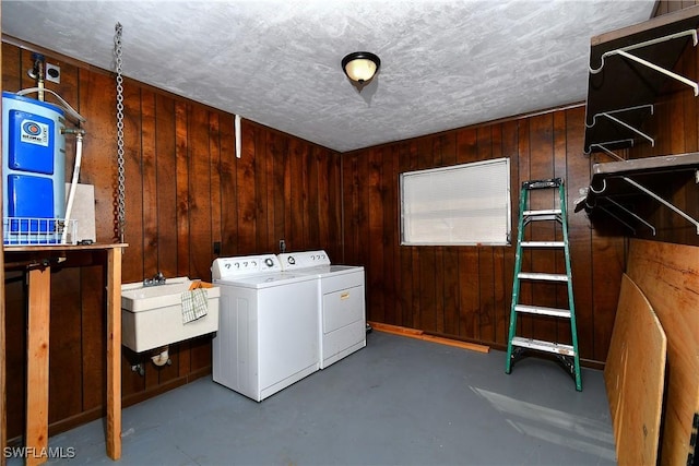 laundry area with laundry area, wooden walls, a textured ceiling, separate washer and dryer, and a sink