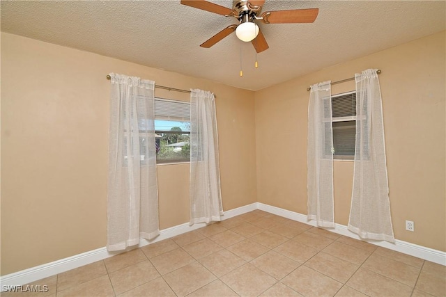 spare room with light tile patterned floors, a textured ceiling, and baseboards