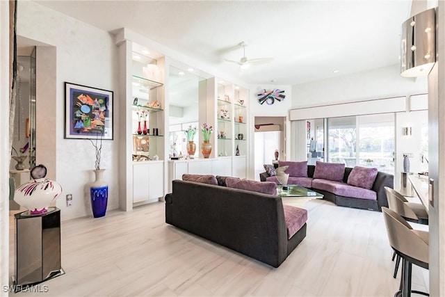 living room with light wood-type flooring, ceiling fan, and built in features