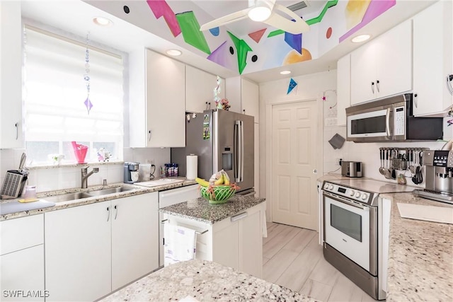 kitchen featuring white cabinetry, light stone countertops, sink, appliances with stainless steel finishes, and decorative backsplash