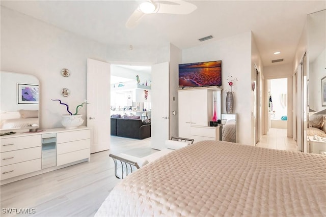 bedroom with ensuite bathroom, light hardwood / wood-style floors, and ceiling fan