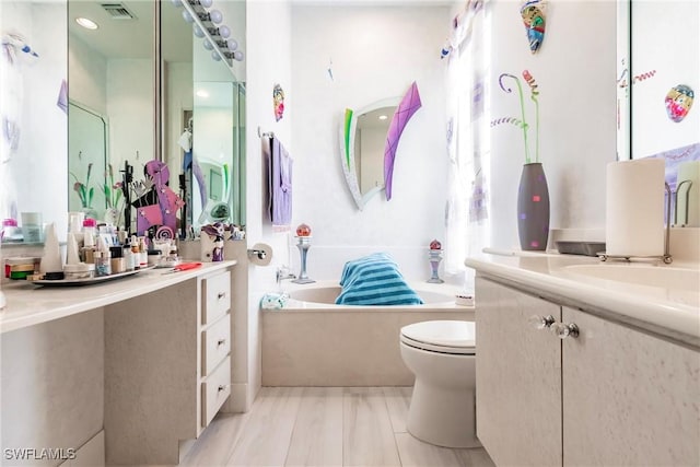 bathroom featuring vanity, toilet, and a tub