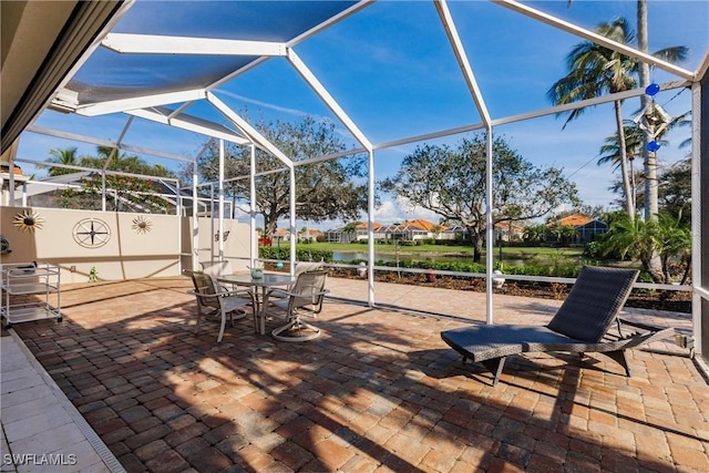 3500 Donoso Ct, Naples, FL 34109 - view of patio featuring glass enclosure, outdoor dining space, and a water view