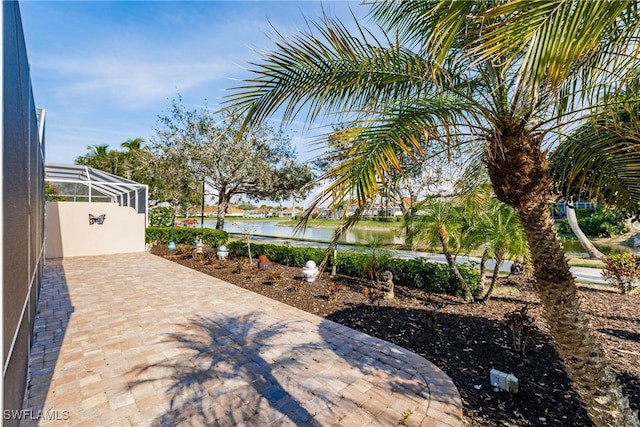 view of patio featuring a water view and a lanai