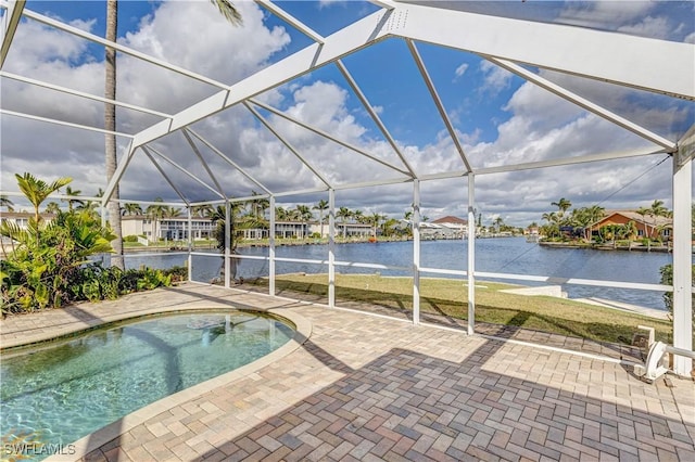 pool with glass enclosure, a patio, and a water view