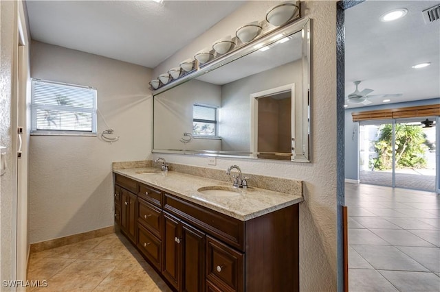 full bathroom with double vanity, tile patterned floors, a sink, and baseboards