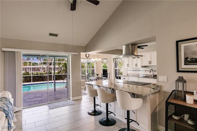 kitchen featuring a kitchen breakfast bar, light stone counters, white cabinets, sink, and kitchen peninsula