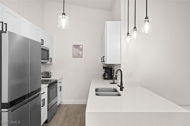 kitchen with white cabinetry, appliances with stainless steel finishes, sink, and pendant lighting