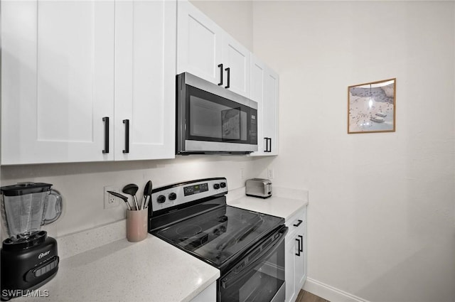 kitchen with electric stove and white cabinetry