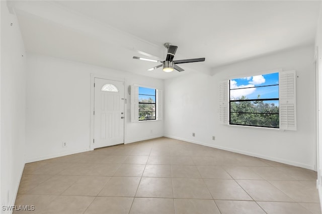 empty room with light tile patterned flooring, a ceiling fan, and baseboards