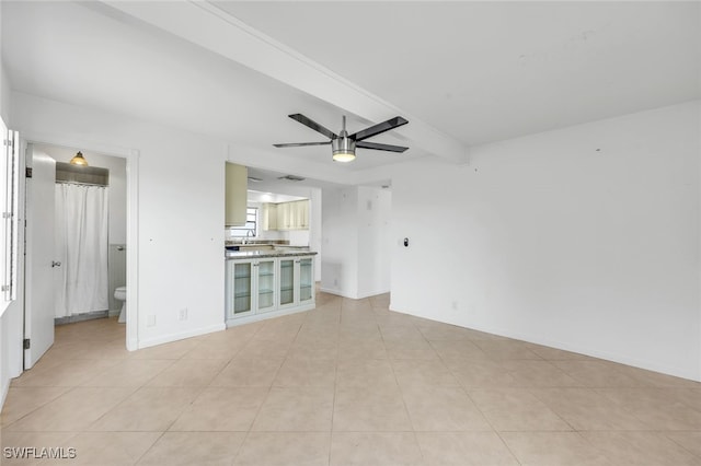 unfurnished living room with a ceiling fan, beamed ceiling, baseboards, and light tile patterned floors