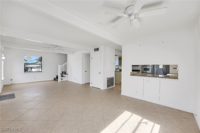 unfurnished living room with light tile patterned floors, ceiling fan, and stairs