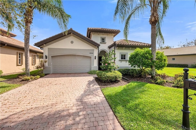 mediterranean / spanish home featuring a front lawn, decorative driveway, an attached garage, and stucco siding